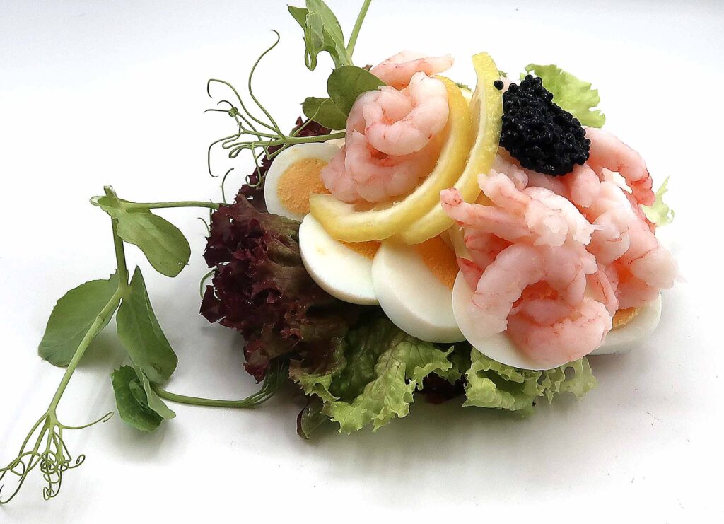 Luksus æg og rejer, med citron, og kaviar pyntet med grønt. Anrettes på dansk solsikke rugbrød